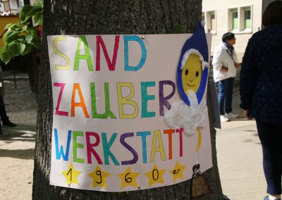 Ein Schild auf dem steht: Sand Zauber Werkstatt. Inspiriert und mit einem Bild vom Sandmann