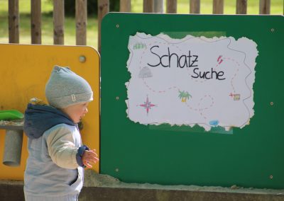 Ein Schild auf dem steht: Schatzsuche. Es Ging um eine Schatzsuche in unserem Sandkasten