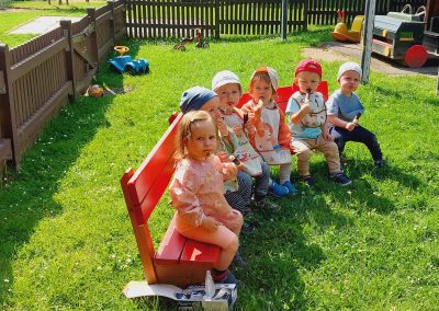 Unser jüngste Sitzen auf einer Bank. Sie schlecken ihr Eis und schauen in die Kamera.