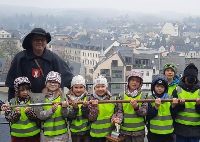 Kinder und der Nachtwächter halten die Hellbarde des Nachtwächters. Im hintergrund sieht man Lichtenstein von oben.