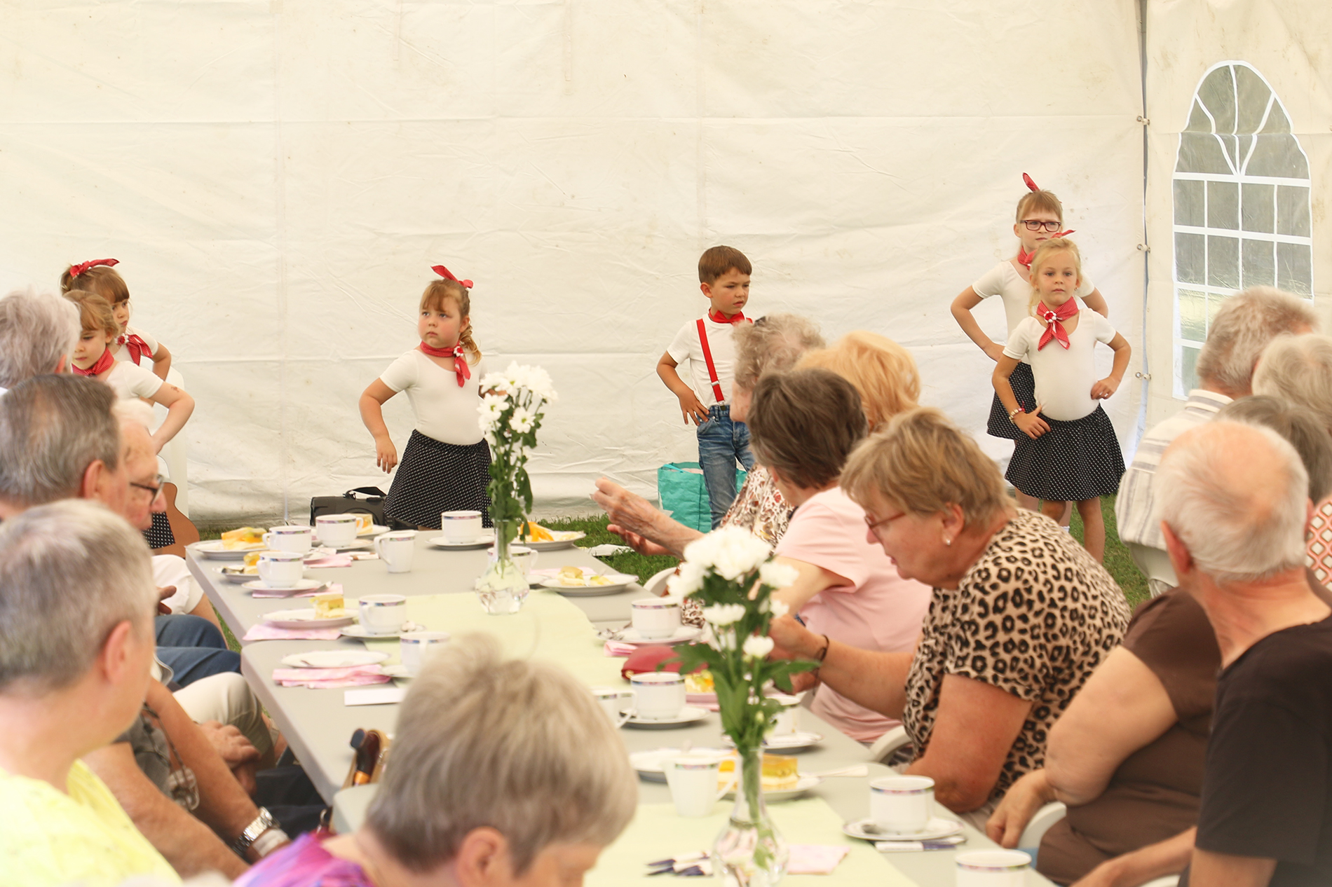 Kinder aus der Kita Flax & Krümel tanzen zum Sommerfest vor den Bewohnern